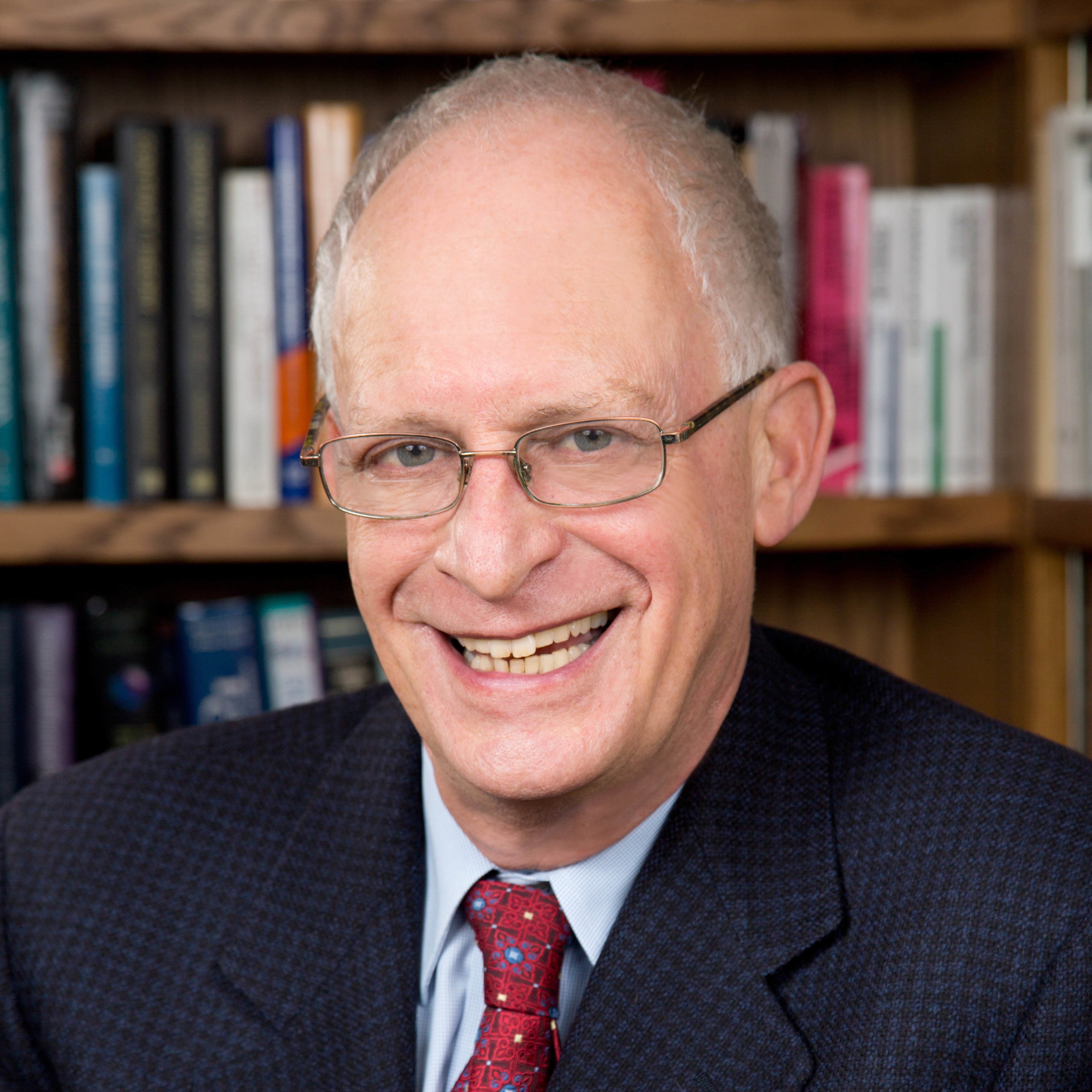 Professor Sir Oliver Hart, 2016 Nobel Prize winner, white man with grey hair, blue eyes, smiling behind glasses