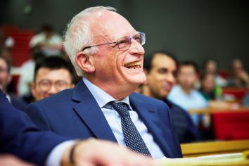 Photo of Sir Oliver Hart, Nobel Laureate, sitting in front row, smiling, in attendance at the inauguration of the lecture series bearing his name