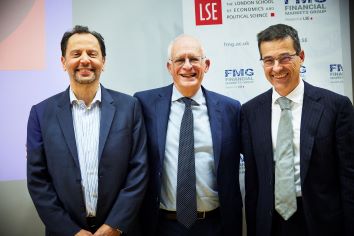 Three males academics posing in front of FMG banner after lecture, left to right, Luigi Zingales, Sir Oliver Hart, Dimitri Vayanos