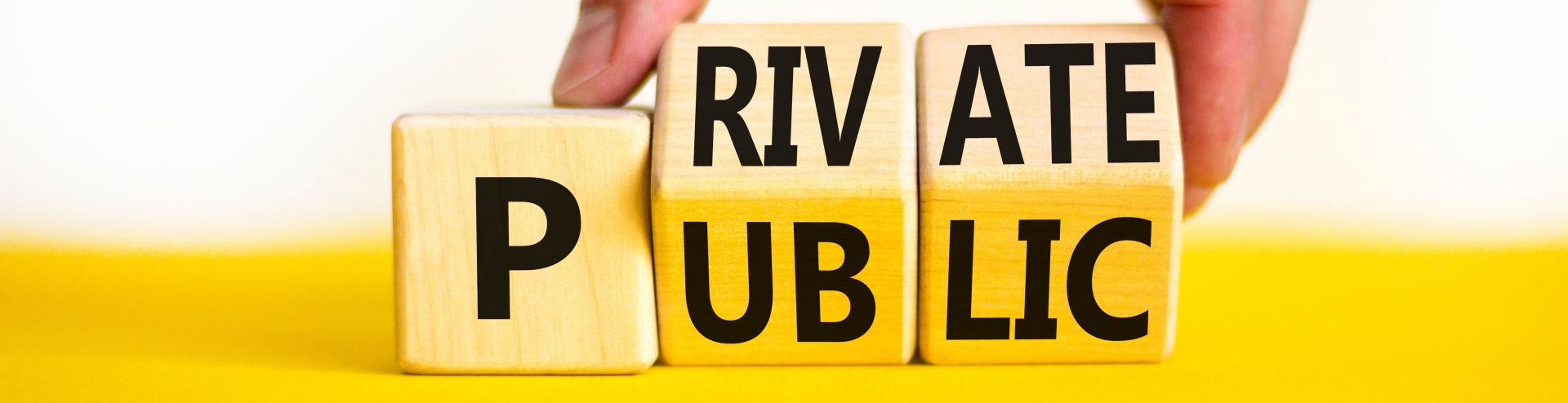 Private or public symbol. Concept words Private or Public on wooden cubes. Businessman hand. Beautiful yellow table white background. Business and private or public concept.